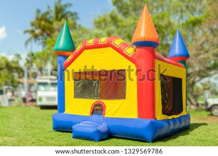 A simple but colorful castle bounce house. The inflated bounce house with pops of color sits at the park on a beautiful sunny day.