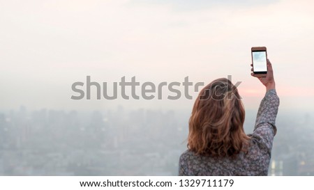 Woman capturing a photo of the sunset