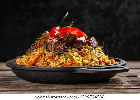 The concept of oriental cuisine. National Uzbek pilaf with meat in a cast-iron skillet, on a wooden table. background image. top view, copy space, flat lay Royalty-Free Stock Photo #1329724586