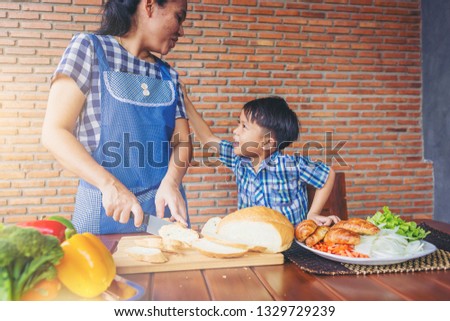 Mother and son preparing food, cooking meal together in the kitchen.