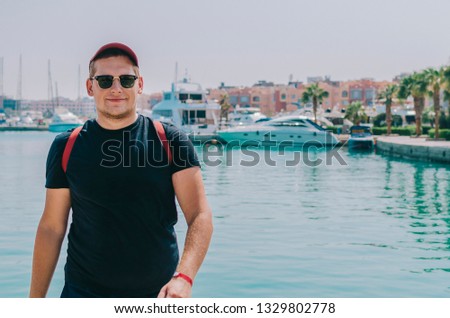 Man in cap and glasses in summer port on sea