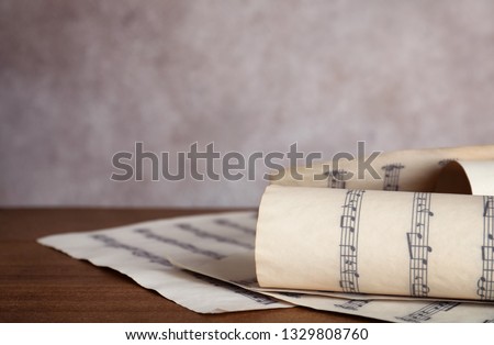 Music sheets with notes on table against color background, closeup. Space for text