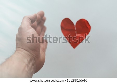 The concept of a broken heart, the end of love, rejection, divorce. The male hand let go of the damaged heart.
