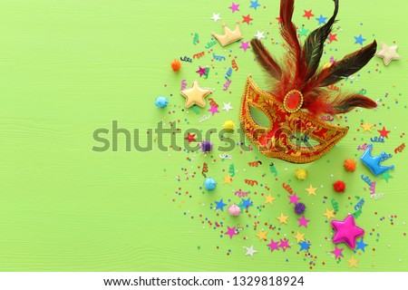 carnival party celebration concept with mask over green wooden background. Top view. Flat lay