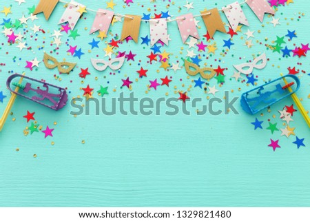 Party colorful confetti with noisemaker over light pastel blue wooden background . Top view, flat lay