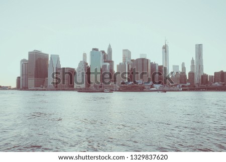 New York Financial District and the Lower Manhattan in the evening viewed from the Brooklyn Bridge Park. Low contrast color image.