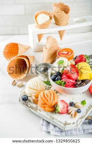 Colorful fruit and berry, nut, chocolate and vanilla ice cream, with waffle ice-cream cones, with fresh fruit and berries, top view copy space white marble background