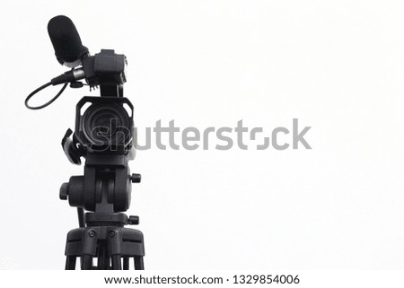 The video camera with the tripod isolated on white background.