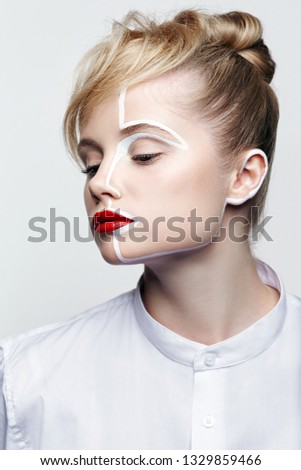 Beauty fashion portrait of a young woman on gray background. Female with an unusual creative makeup face painting