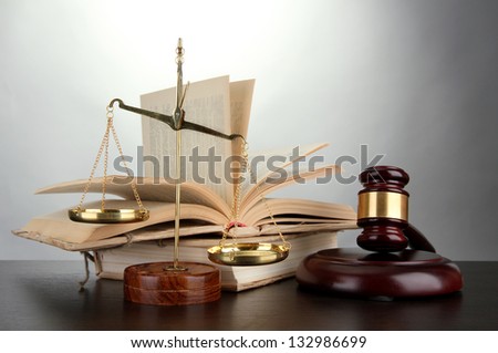 Golden scales of justice, gavel and books on grey background
