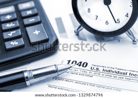 Tax form with clock, calculator and pen. Tax time. toned image.