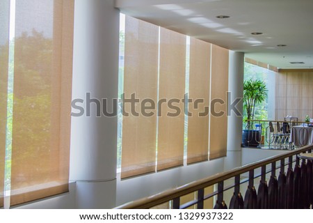 Close up luxury Long blind, curtain, protected sunlight with large glass wall and green tree background. Royalty-Free Stock Photo #1329937322