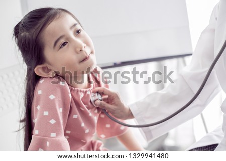Asian doctor examining a little girl by stethoscope