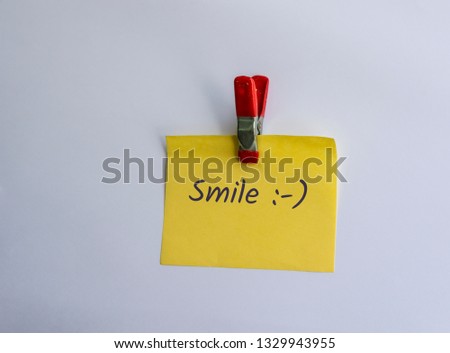 Smile written on clipped yellow note 