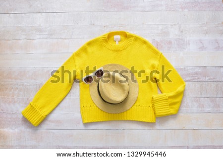 Yellow sweater with hat ,sunglasses on white wooden background
