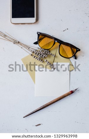 Blogger/freelancer desk concept with sunglasses, blank paper, phone, accessories, envelope. Top view