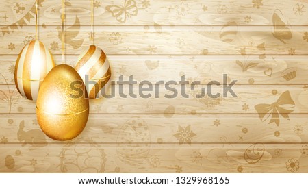 Several golden Easter eggs hanging on background of wooden planks with holyday symbols like flowers, cakes, hare, hen, chicken, bow and other