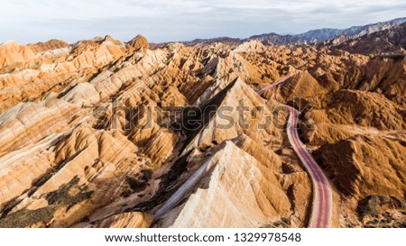 Top View of Rainbow Mountains Geological Park. Stripy Zhangye Danxia Landform Geological Park in Gansu Province, China. Drone Picture of Road in a Valley on a Sunny Day.