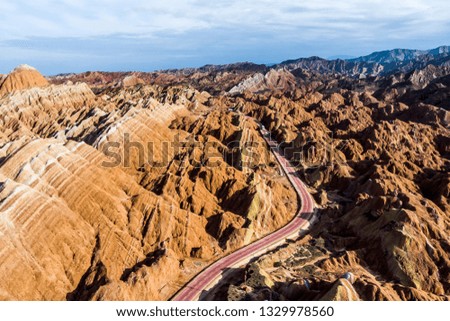 Top View of Rainbow Mountains Geological Park. Stripy Zhangye Danxia Landform Geological Park in Gansu Province, China. Drone Picture of Tourist Buses on a Road in a Valley on a Sunny Day.