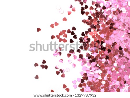 Pink glitter hearts on white background. Close-up of shiny confetti.