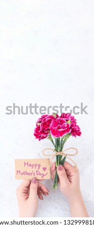 May mothers day idea concept photography - Beautiful blooming carnations tied by rope kraft bow holding in woman's hand isolated on bright modern table, copy space, flat lay, top view