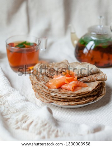 Stack of home made delicious blini of  buckwheat flour served with fresh smoked salmon and sour cream. Gourmet breakfast. White knitted plaid as backgound Maslenitsa, Russia Mardi gras France