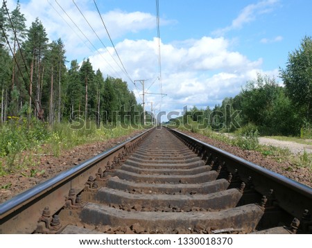 Photo of the railroad below in the forest with a beautiful blue sky and clouds on a warm summer day