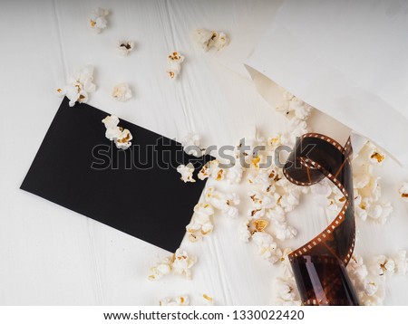 photographic film strip on white wooden background, popcorn.