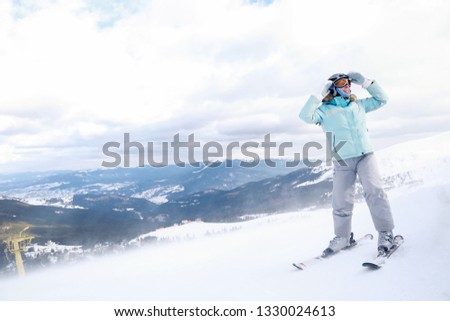 Adult caucasian woman skier rides a ski resort on a background of mountains and ski resort in down 