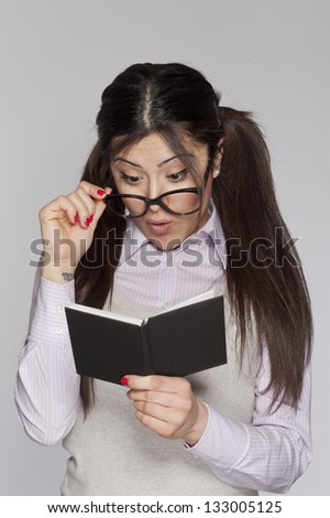 Young surprised nerd woman studying on white background