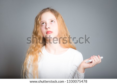 cute girl child thinking with a phone in hand, studio photo over background