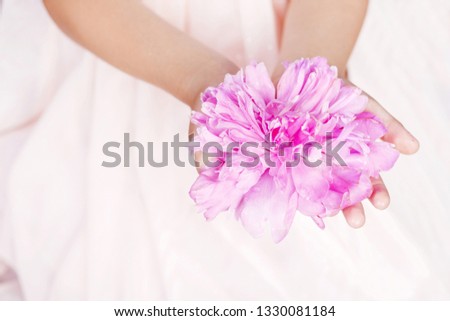 Girl holding a pink peony flower in hand. Close up picture. Copy space