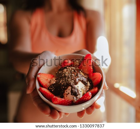young woman with sports bra eating breakfast bowl of fruit yogurt seeds and chocolate
