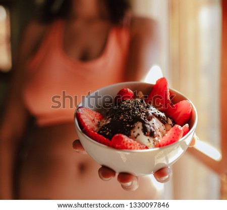 young woman with sports bra eating breakfast bowl of fruit yogurt seeds and chocolate