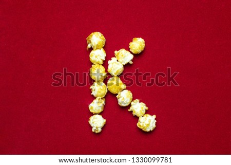 English alphabet from cinema popcorn. Letter K. Red background for design. Movie styling.