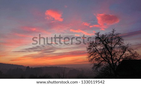 Beautiful early morning autumn sky illuminates the picturesque rural landscape. Vibrant colors and puffy clouds above the foggy forests of Slovenia. Idyllic fall sunset in the scenic countryside.