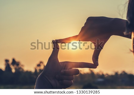 hands making framing view distant over sunset