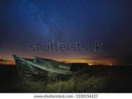 Beautiful nightscape with old wooden boat, starry sky and Milky way galaxy.