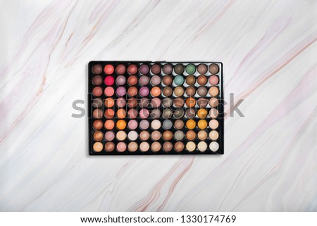 Eyeshadow palette on marble texture with natural pattern. Different eyeshadow colors. Flat lay. Top view
