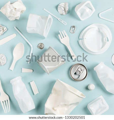 White single use plastic on  blue background.
 Environmental, pollution concept. Flat lay, top view