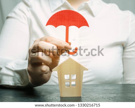 A woman is protecting a miniature wooden house. Property insurance concept. Protection of housing. Security and safety. Family and life insurance. Service. Agent. Support