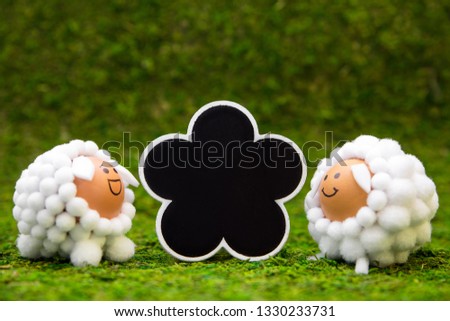 Cute selfmade lamb figures and slate on green meadow, copyspace for spring and easter theme