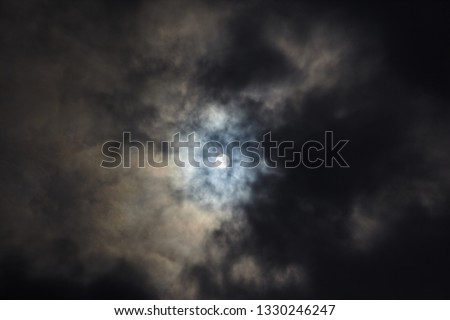 Solar partial eclipse, photos of moon covering the sun with light cloud cover. Gloomy and beautiful clouds

