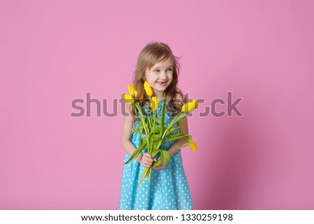 Beautiful blonde girl holding Yellow tulips and a card for a holiday gift on pink . Celebration of International women's day. Concept of holidays, people and beauty.