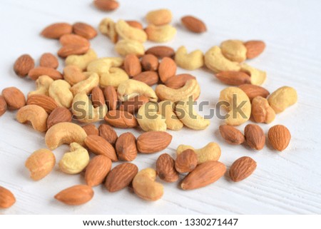 mixed nuts with selective focus on neutral background. Roasted almond and cashew nuts. Delicious natural healthy protein snack. Cashews and almonds nut for vegan daily nutrition 