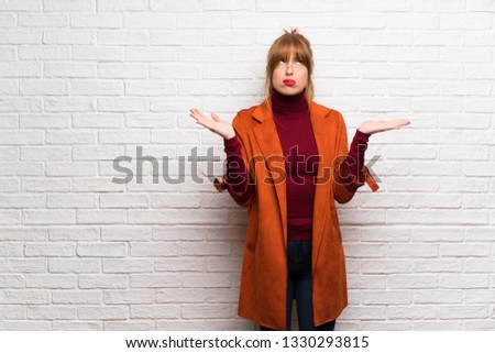 Woman with coat over white brick wall frustrated by a bad situation