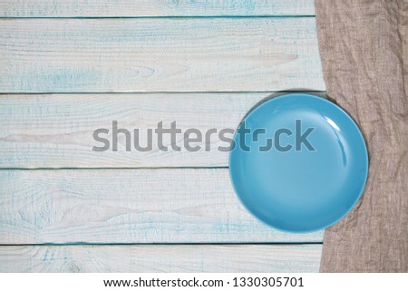 Empty blue plate and  gray napkin on a wooden background, with copy space.