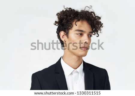Curly guy in a suit on a gray background office worker
