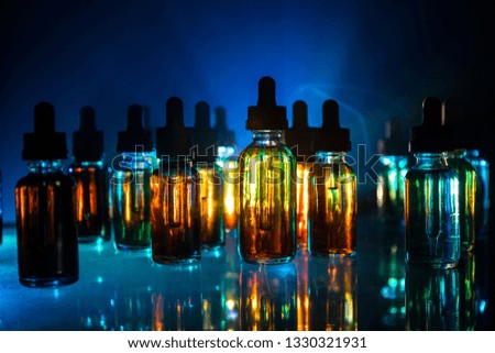 Vape concept. Smoke clouds and vape liquid bottles on dark background. Light effects. Useful as background or electronic cigarette advertisement. Selective focus