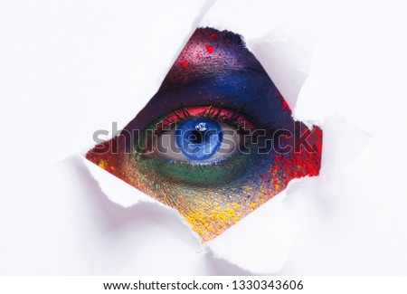 Business card of artist, beauty concept. Female eye whith bright make up through hole in paper